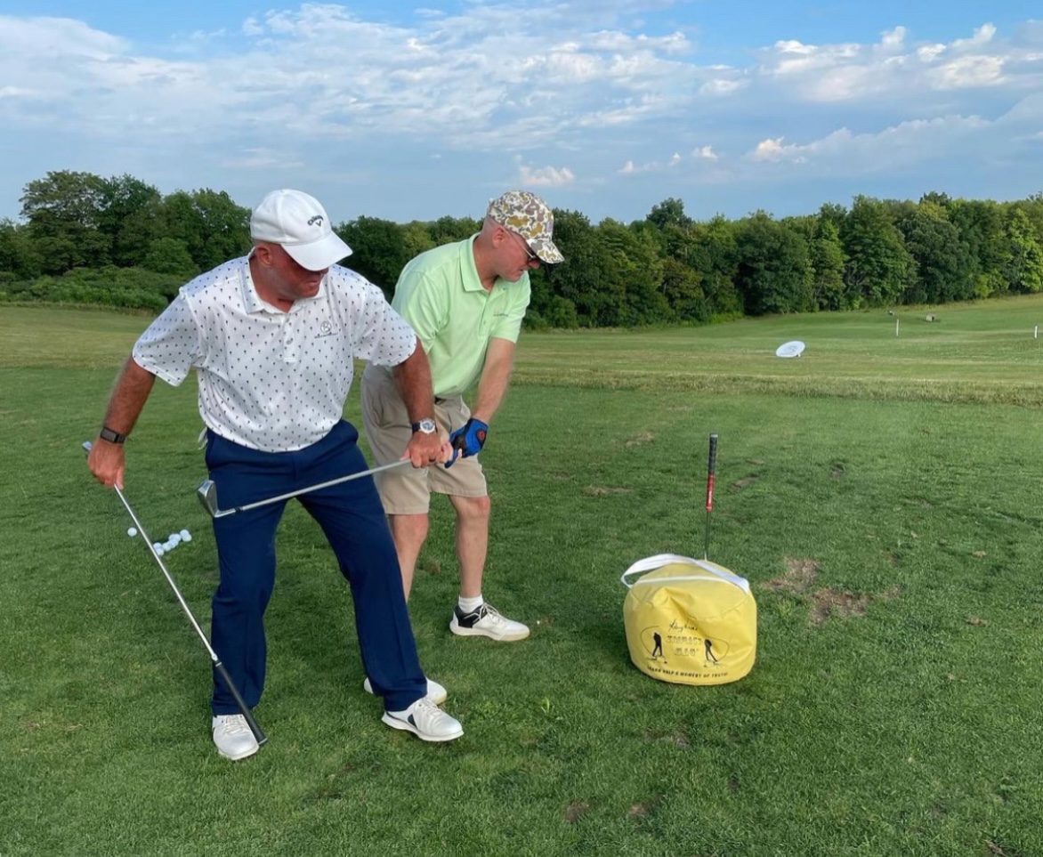 Brian Jacobs instructing an adult golfer on the range at Eagle Vale